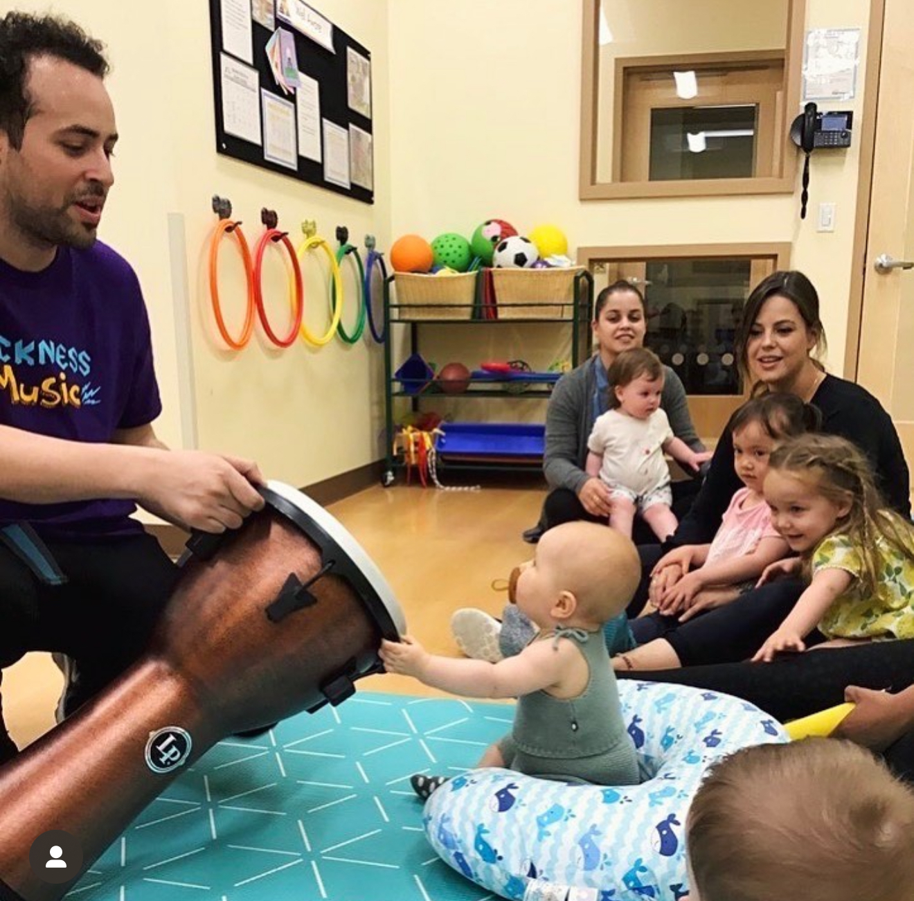 Rockness Music teacher helping a preschooler explore a small drum during an early childhood music class, Music Classes For Kids In Park Slope
